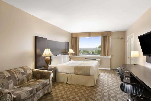 北湾Days Inn & Suites by Wyndham North Bay Downtown的酒店客房,配有床和沙发