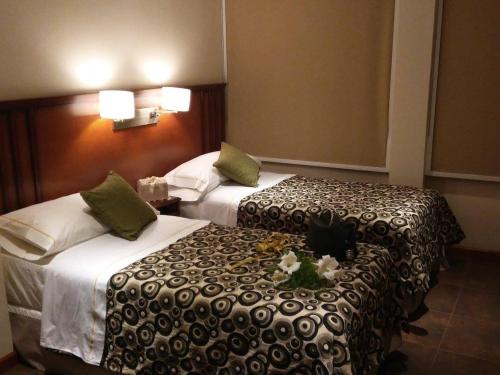 布宜诺斯艾利斯Hotel Irun的床铺上的两张床铺,酒店房间床上有鲜花