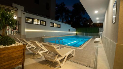 安塔利亚OPERA SUITES Apart Hotel的一个带白色椅子的游泳池和一个游泳池