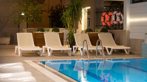 安塔利亚OPERA SUITES Apart Hotel的一组白色椅子,位于游泳池旁