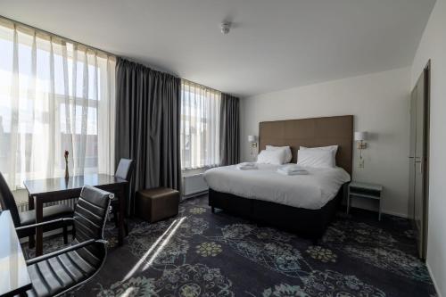 法尔肯堡Atlas Hotel的酒店客房设有一张床、一张书桌和窗户。