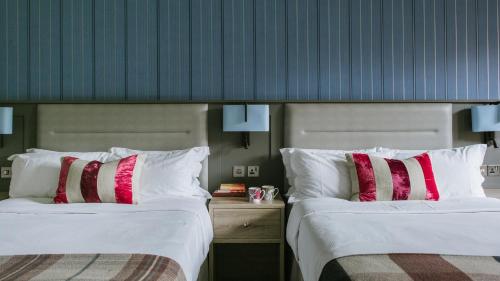 特灵盆德雷庄园酒店的两张位于酒店客房的床,配有红色和白色枕头