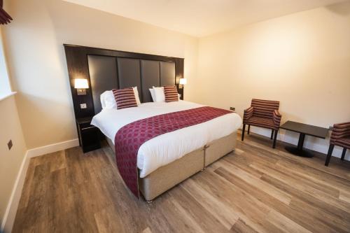 维斯贝希Crown Lodge Hotel的酒店客房带一张大床和两张椅子
