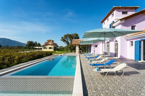 伊奥斯克里克斯Aneli Luxury Villas - Villa Alexandra的房屋旁的游泳池配有椅子和遮阳伞