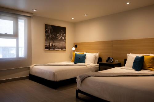 圣胡安The Ivy Hotel的酒店客房设有两张床和窗户。