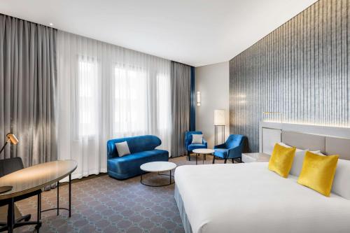 悉尼悉尼丽笙世嘉酒店的酒店客房带大床和蓝色椅子