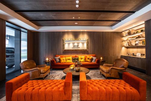嘉义市巨升嘉义亮点旅店的客厅配有橙色沙发、桌子和椅子