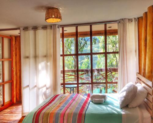 圣特雷莎盖丘亚生态山林小屋的一间卧室设有一张床和一个大窗户