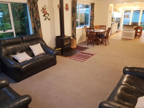 HampdenTui Cottage的客厅配有真皮沙发和木柴炉。