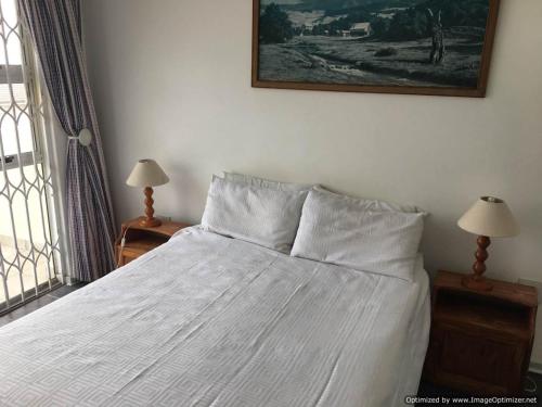 马盖特Ipanema 6的卧室内的一张带白色床单和枕头的床