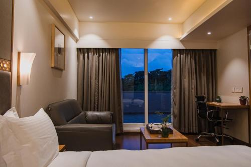 博帕尔Safal Retreat的酒店的客房 - 带一张床、椅子和窗户