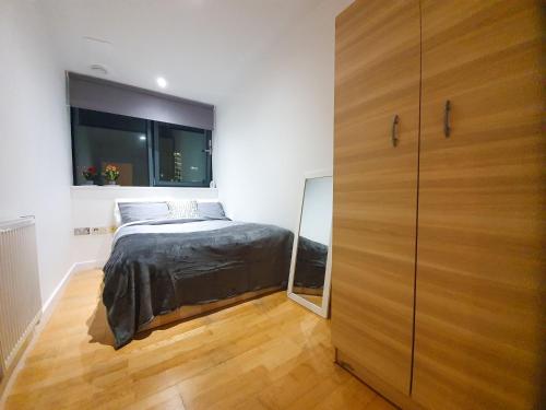 伦敦LiveStay-Modern 3 Bed Apt on 8th Floor with Amazing Views的一间卧室配有一张床和一个大型木制衣柜