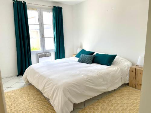 里夫杜海滩COUP DE CŒUR - ILE DE RE - Maison 3 chambres的卧室配有带蓝色枕头的大型白色床