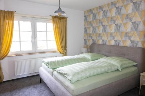 比斯平根Heidehof Jungemann的一间卧室配有床和两个窗户,窗户配有黄色窗帘