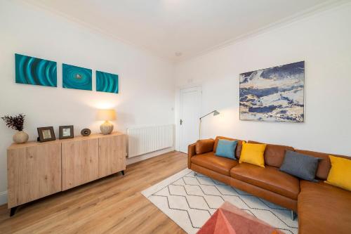 邓迪Abbotsford Apartment的客厅配有沙发和墙上的绘画