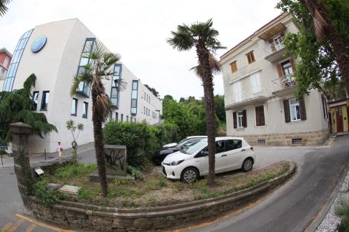 波尔托罗Apartments Morski Svet Portorož的棕榈树建筑旁的白色汽车