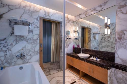 新德里康诺特广场丽笙酒店的带浴缸、水槽和镜子的浴室