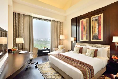 诺伊达诺伊达丽筠酒店的酒店客房设有一张大床和一张书桌。