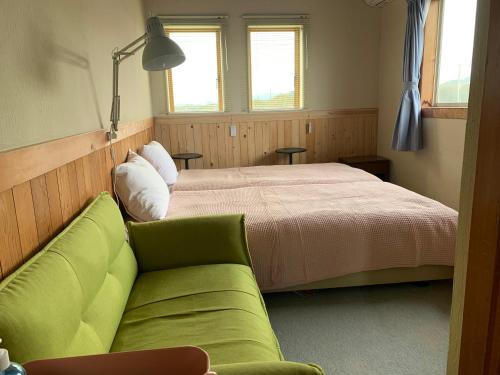 南房总市南鸟住宿加早餐旅馆的一间卧室配有一张床和一张绿色沙发