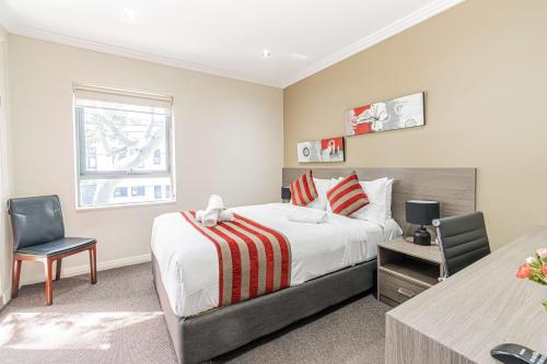 悉尼Best Western Plus Camperdown Suites的一间卧室配有一张床、一张书桌和一个窗户。