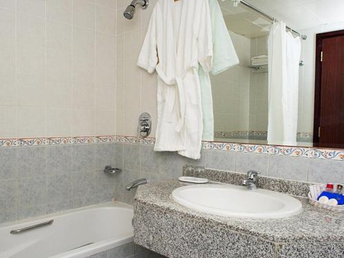 马斯喀特Safeer Plaza Hotel的一间带水槽、浴缸和镜子的浴室