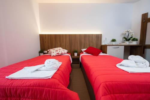 新梅斯托Gostilna Pugelj的宿舍间的两张床,配有红色的床单和毛巾