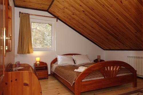 TeshelСемеен хотел Орфей的一间卧室设有一张木床和一个窗户。