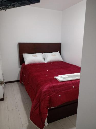 HuancavelicaPYMABET的一张带红色毯子的床和两个枕头