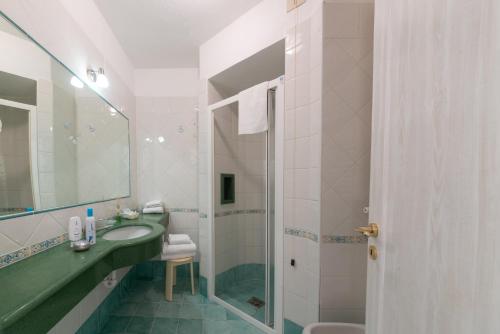 伊斯基亚Villa Bina Sea Hotel的一间带水槽、镜子和淋浴的浴室
