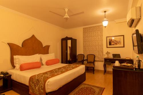 瓦拉纳西Amritara Suryauday Haveli的配有一张床和一张书桌的酒店客房