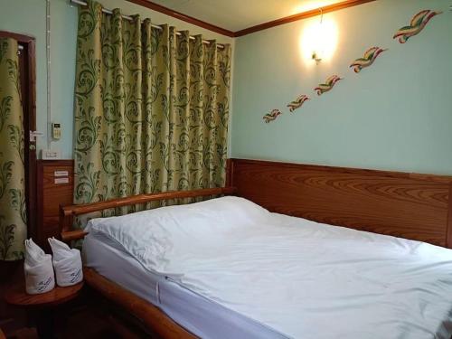 Ban Pa Waiเพชร รีสอร์ท นครไทย-Phet Resort, Nakhonthai的卧室配有带窗帘的白色床