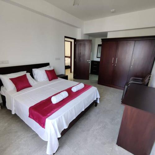 科伦坡Modern apartment in close proximity to the Beach的一间卧室配有一张带红色和白色枕头的大床