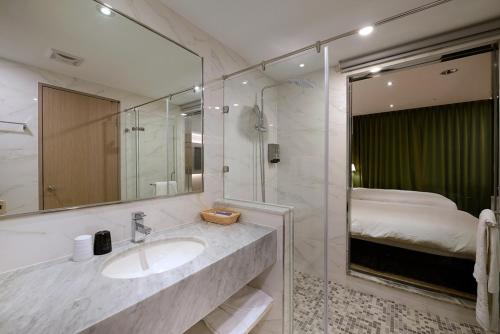 台中市台中爱丽丝国际大饭店的一间带水槽和镜子的浴室以及一张床