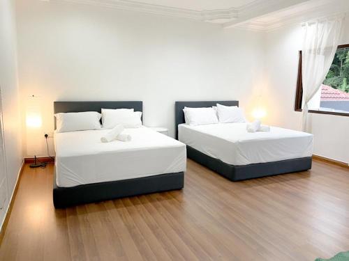 吉隆坡Mas Homestay的配有白色墙壁和木地板的客房内的两张床