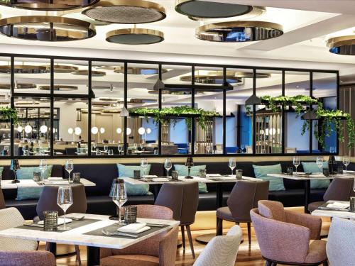 雅典Athens Capital Center Hotel - MGallery Collection的餐厅设有桌椅和窗户。