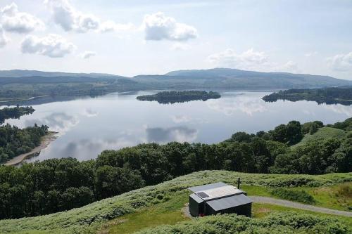 Loch AweOdhrán Lodge, St Conan's Escape: Home with a view的一座小建筑,位于一座小山上,俯瞰着湖泊