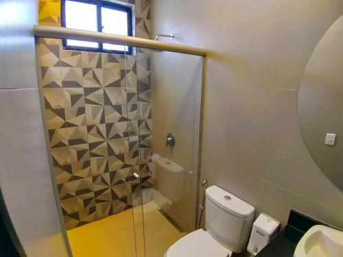 贝洛奥里藏特Motel Caribe的一间带卫生间和玻璃淋浴间的浴室