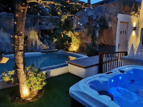 圣马克西姆Casa Louise Suites and Spas privatifs的花园内的一个按摩浴缸,花园内有树