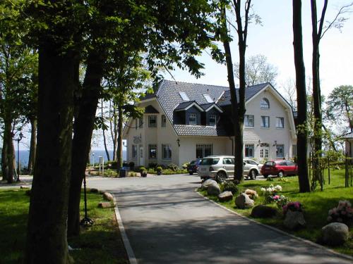 费马恩沃尔德帕维轮旅馆的一座大型白色房子,前面有汽车停放