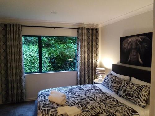 奥克兰Gulf Harbour Guest House Apartment的一间卧室设有一张床和一个大窗户