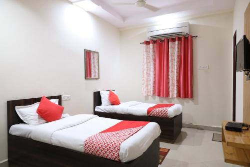 DhantoliOYO Prithvi Inn的配有红色窗帘的客房内的两张床