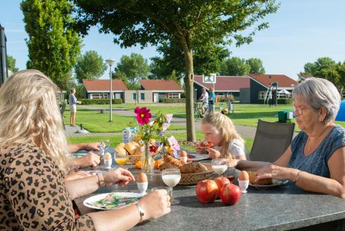 柯德科克Vakantiepark Broedershoek的一群坐在餐桌上吃食物的人