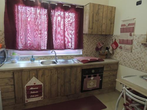 特雷比萨切Casa Vacanze “Playa”的带水槽的厨房和带红色窗帘的窗户