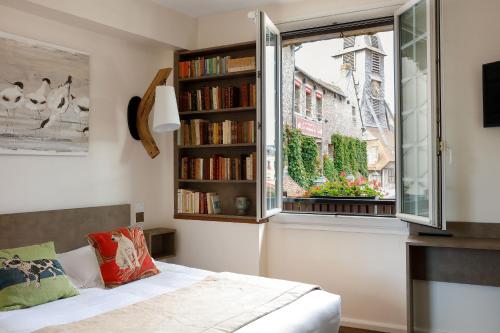 翁弗勒尔Hotel Le Dauphin的一间卧室设有床铺和窗户,备有书籍