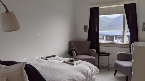 FlateyriFlateyri guesthouse的卧室配有床、椅子和窗户。