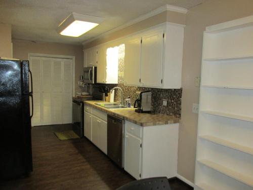 凯斯Cayce Charm Minutes to Downtown Columbia的厨房配有白色橱柜和黑色冰箱。