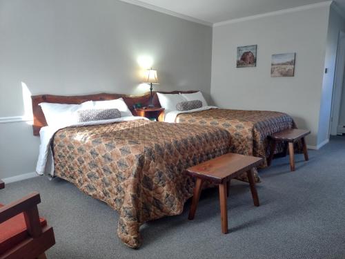 NewfaneThe Lodge at West River的酒店客房设有两张床和一张桌子。