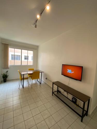 彼得罗利纳Vale Hospedar Paulo Coelho Apart的客厅配有桌子,墙上配有电视