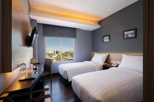 泗水BATIQA Hotel Darmo - Surabaya的酒店客房设有两张床和窗户。