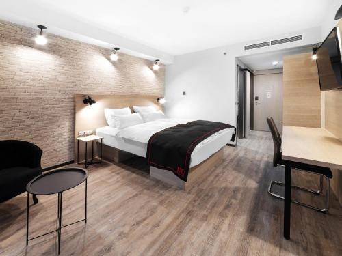 布达佩斯DORMERO Hotel Budapest的配有一张床和一张书桌的酒店客房